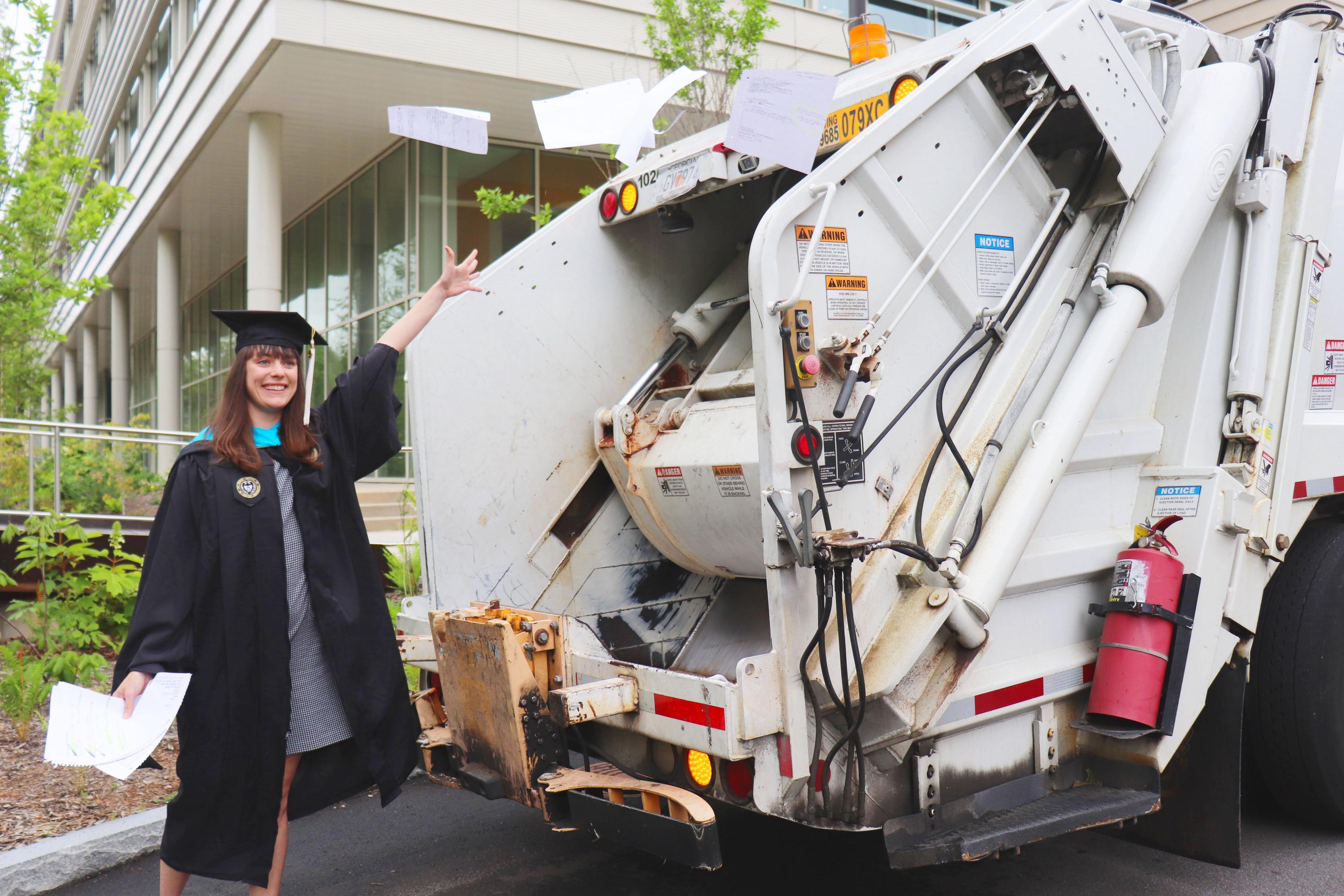 image of Emma Brodzik in master's garb with recycling truck